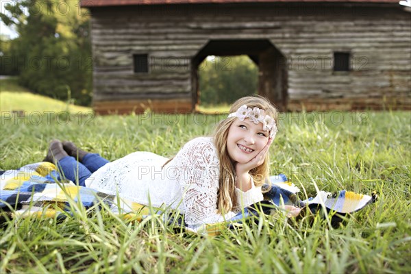 Caucasian girl laying in grass on farm