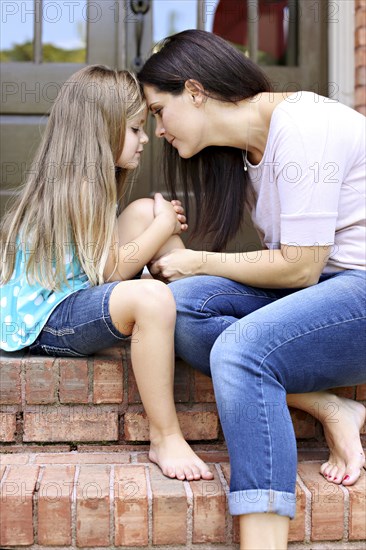 Close up of mother and daughter sitting on front stoop