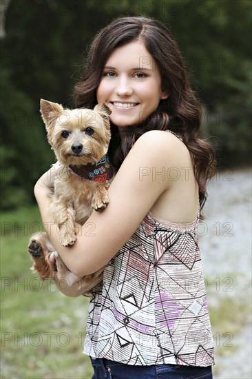 Teenage girl carrying puppy in rural field