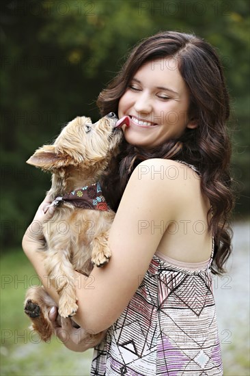 Teenage girl carrying puppy in rural field