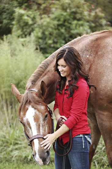 Teenage girl walking horse in rural field