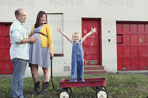 Parents watching son cheering in toy wagon