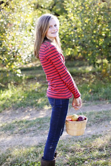 Caucasian girl picking fruit in orchard