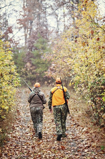 Hunters in camouflage carrying rifles in forest