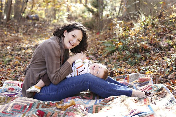 Mother and baby daughter playing on blanket in forest