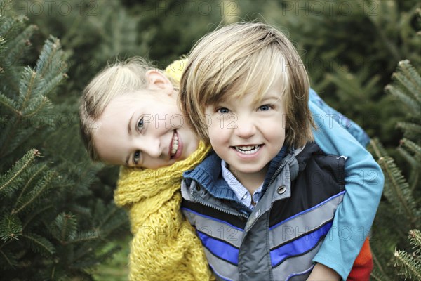 Siblings hugging near pine trees