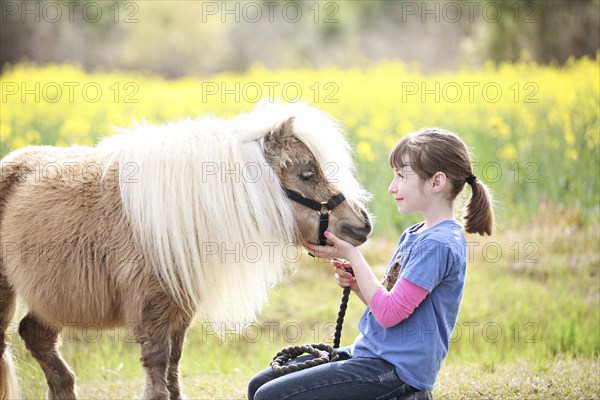 Caucasian girl petting pony in rural field