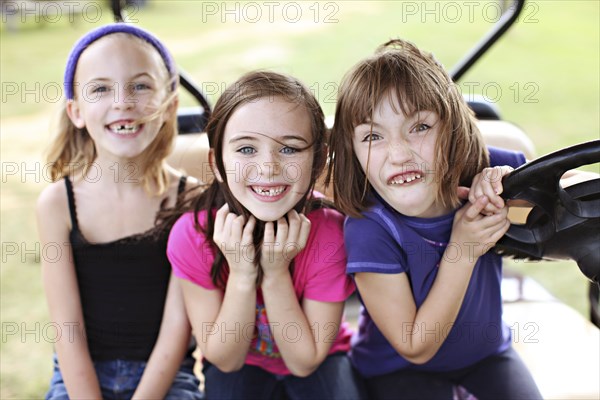 Caucasian girls making faces in golf cart