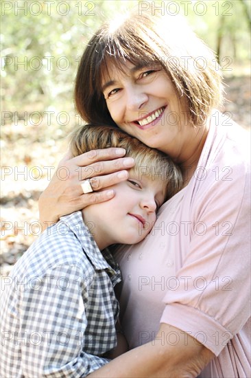 Grandmother and grandson hugging in forest