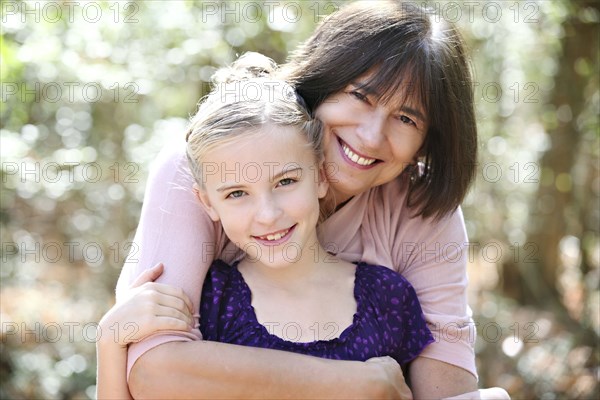 Grandmother and granddaughter hugging in forest