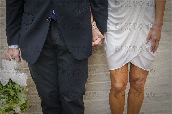 Close up of bride and groom holding hands