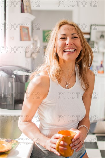 Mixed race woman drinking coffee in kitchen