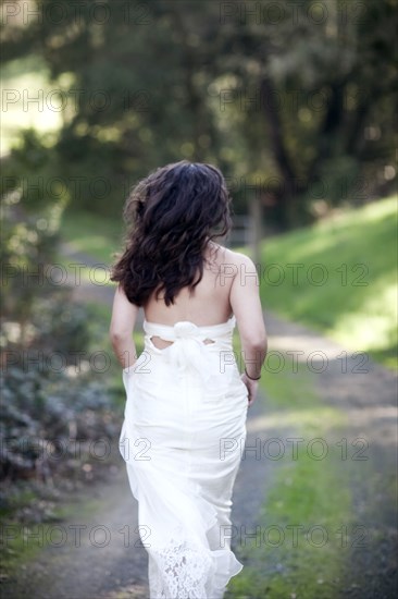 Rear view of bride walking on rural dirt road