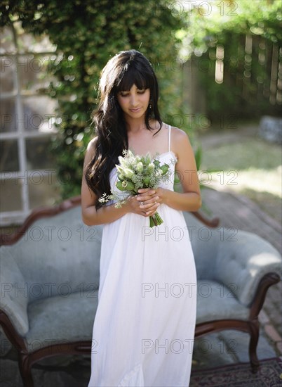 Bride holding bouquet of flowers in backyard