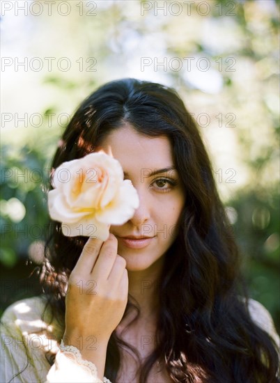 Close up of woman holding rose outdoors