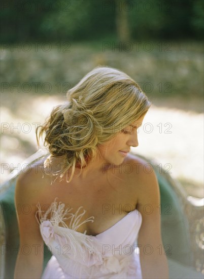 Bride wearing wedding dress on sofa in backyard