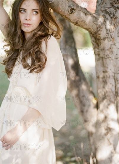 Bride in wedding dress standing under tree