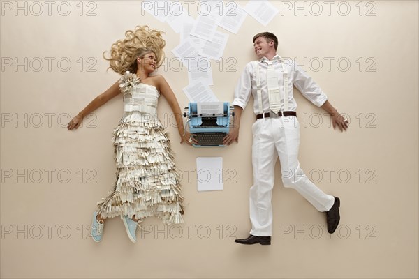 Caucasian couple laying near typewriter on floor