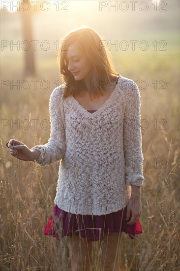 Girl standing in tall grass in rural field