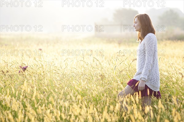 Girl walking in tall grass in rural field