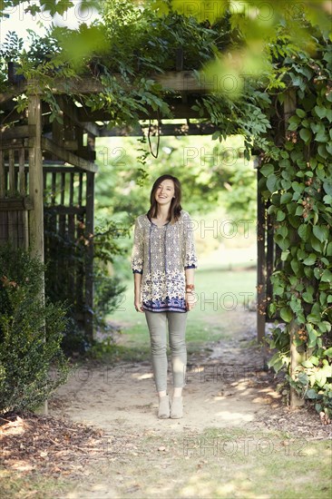 Girl standing under archway in garden