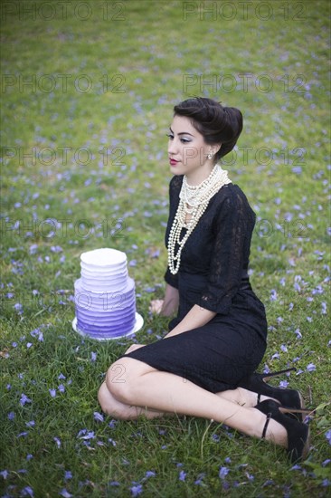 Woman sitting with cake in rural field