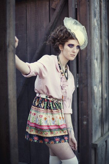 Stylish woman leaning on wooden gate