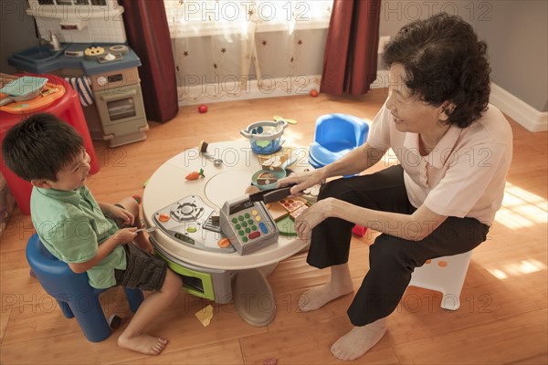 Asian grandmother and grandson playing at table