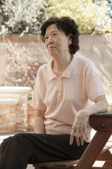 Older Asian woman sitting at picnic table