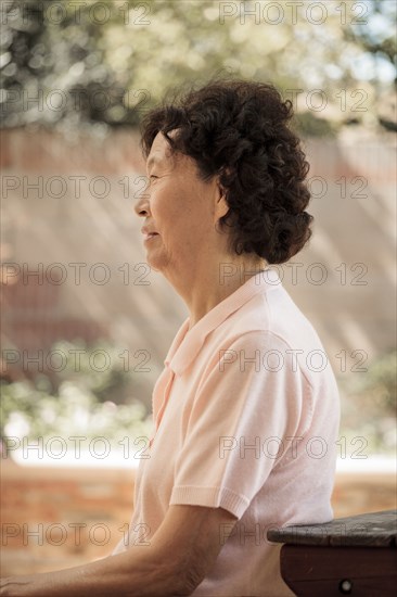 Older Asian woman sitting at picnic table