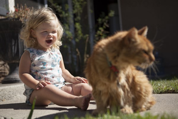 Laughing girl admiring cat in backyard