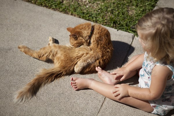 High angle view of girl watching cat in backyard