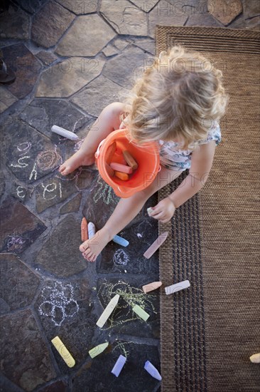 High angle view of girl drawing with chalk on tile