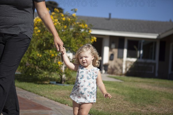 Mother and daughter walking on sidewalk