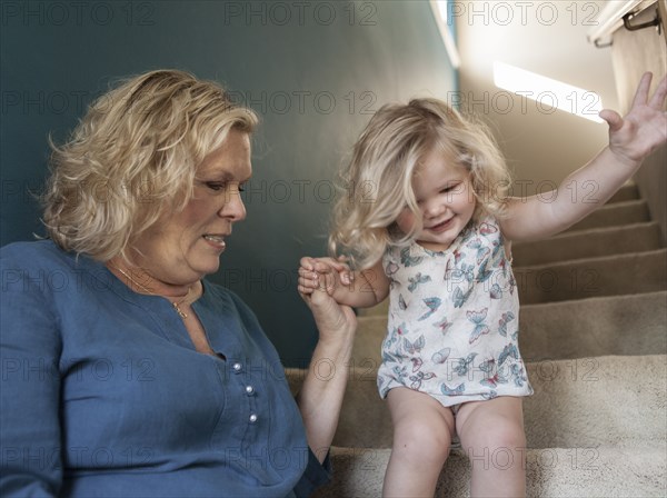 Grandmother helping granddaughter walking on staircase