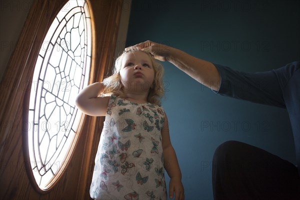 Grandmother patting granddaughter on head near door