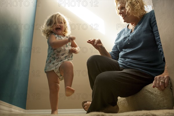 Grandmother watching granddaughter walking on staircase