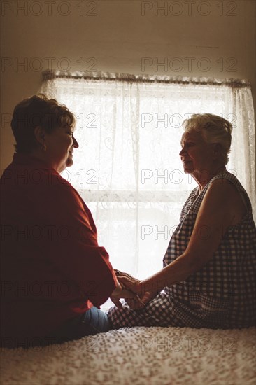 Older woman sitting with daughter on bed