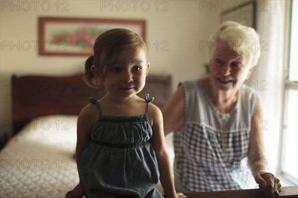 Grandmother and granddaughter sitting on bed