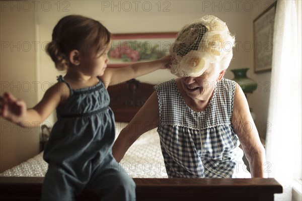 Grandmother and granddaughter playing on bed