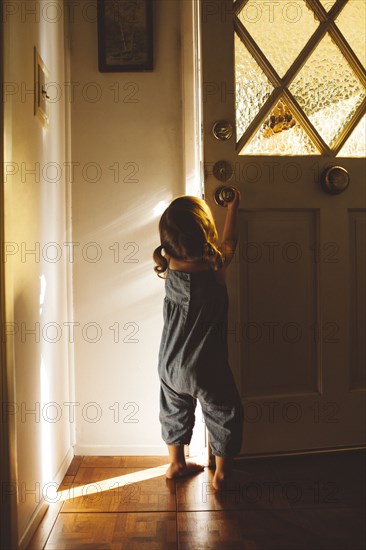 Hispanic preschooler girl opening front door