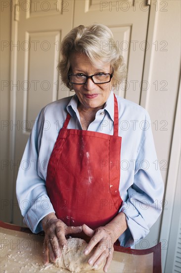 Older woman shaping dough in kitchen