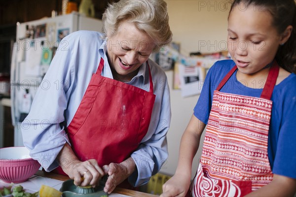 Grandmother and granddaughter squeezing juice in kitchen