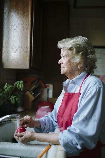 Older woman washing dishes in kitchen sink