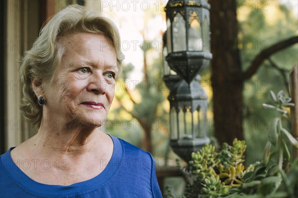 Pensive older woman standing on porch