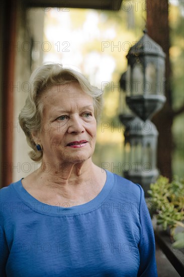 Pensive older woman standing on porch