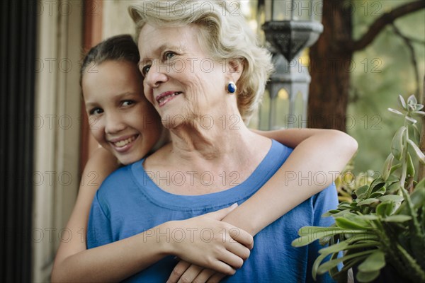 Grandmother and granddaughter hugging on porch