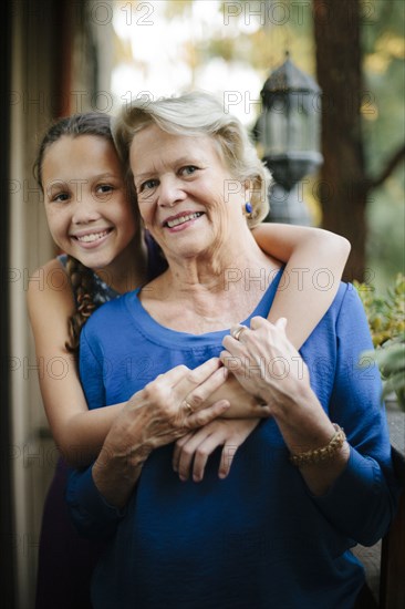 Grandmother and granddaughter hugging on porch