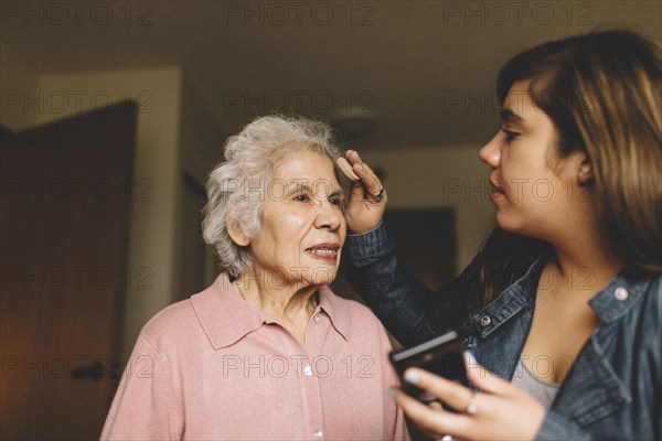 Granddaughter applying makeup on grandmother