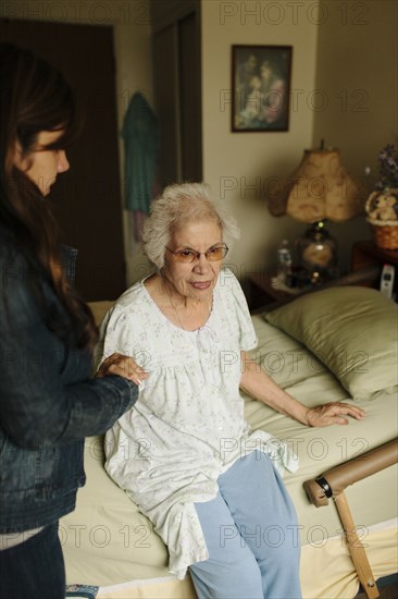 Granddaughter helping grandmother out of bed